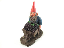 Gnome figurine transporting grapes with a wheelbarrow.  'Christian' Classic gnomes series after a design by Rien Poortvliet.
