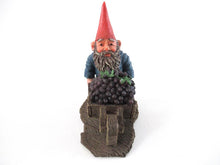 Gnome figurine transporting grapes with a wheelbarrow.  'Christian' Classic gnomes series after a design by Rien Poortvliet.