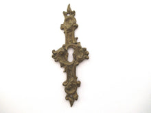 An Antique ornate brass keyhole cover. Ornamental escutcheon, cabinet hardware, furniture applique.