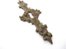 An Antique ornate brass keyhole cover. Ornamental escutcheon, cabinet hardware, furniture applique.