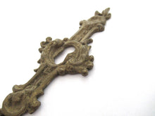 An Antique ornate brass keyhole cover. Ornamental escutcheon, cabinet hardware, furniture applique.