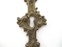 An Antique ornate brass keyhole cover. Ornamental escutcheon, cabinet hardware, furniture applique.