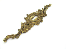 Ornate brass escutcheon, cabinet hardware, furniture applique.