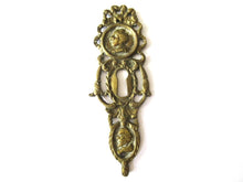 Ornate brass escutcheon, cabinet hardware, furniture applique.