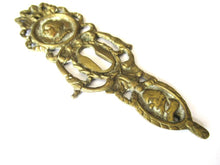 Ornate brass escutcheon, cabinet hardware, furniture applique.
