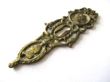 Ornate brass escutcheon, cabinet hardware, furniture applique.