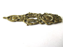 Ornate brass escutcheon, cabinet hardware, furniture applique.