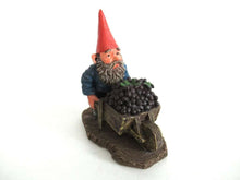UpperDutch:,Gnome figurine transporting grapes with a wheelbarrow 'Christian'.  Classic gnomes series after a design by Rien Poortvliet.